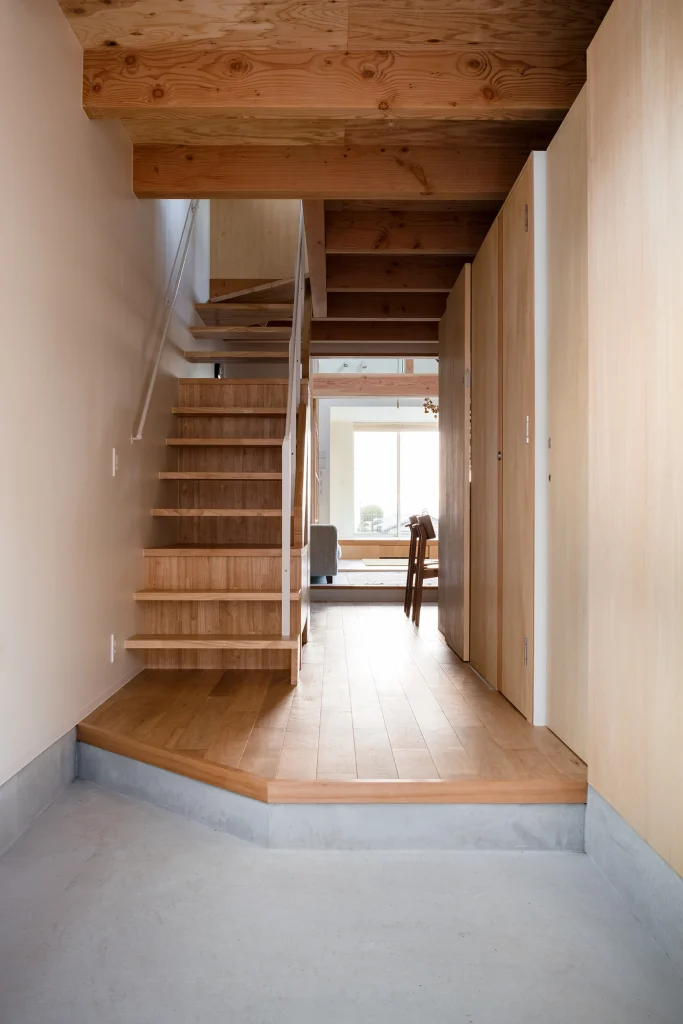 Interior view showing transition from concrete entrance to timber-floored living space.