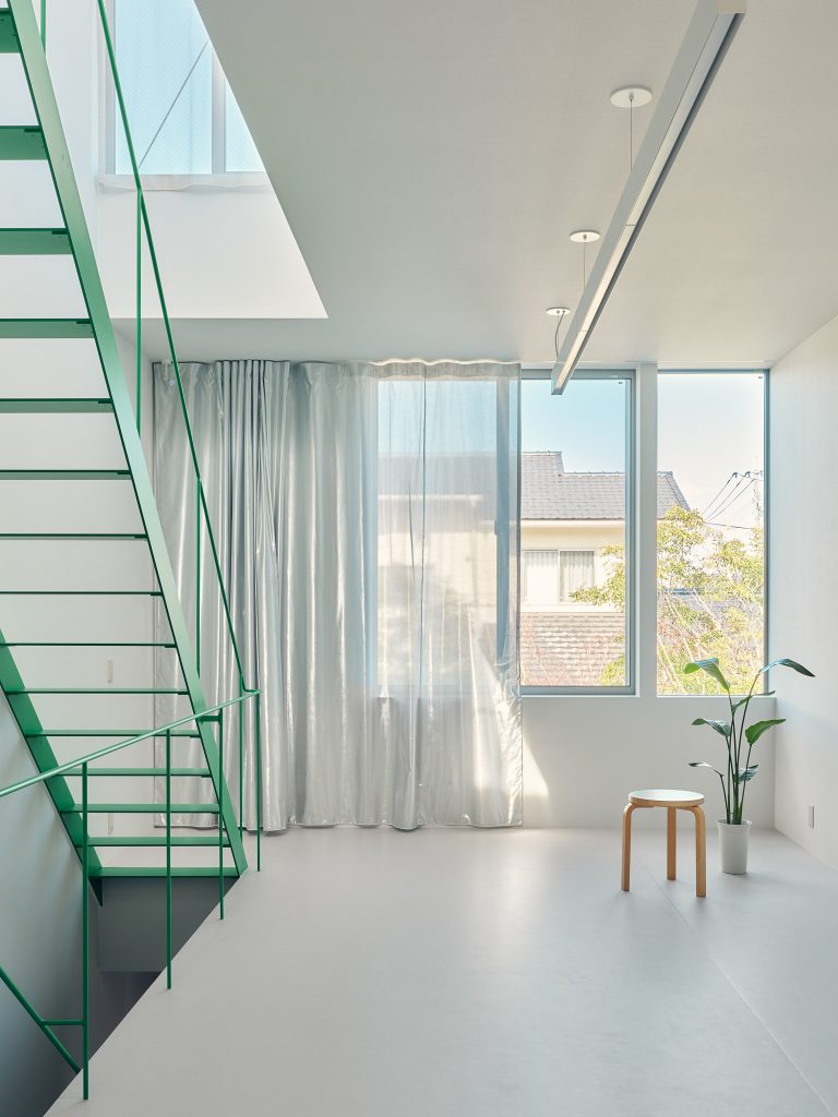 Living area of O-Studio facing a small garden with large windows that open the room to greenery.