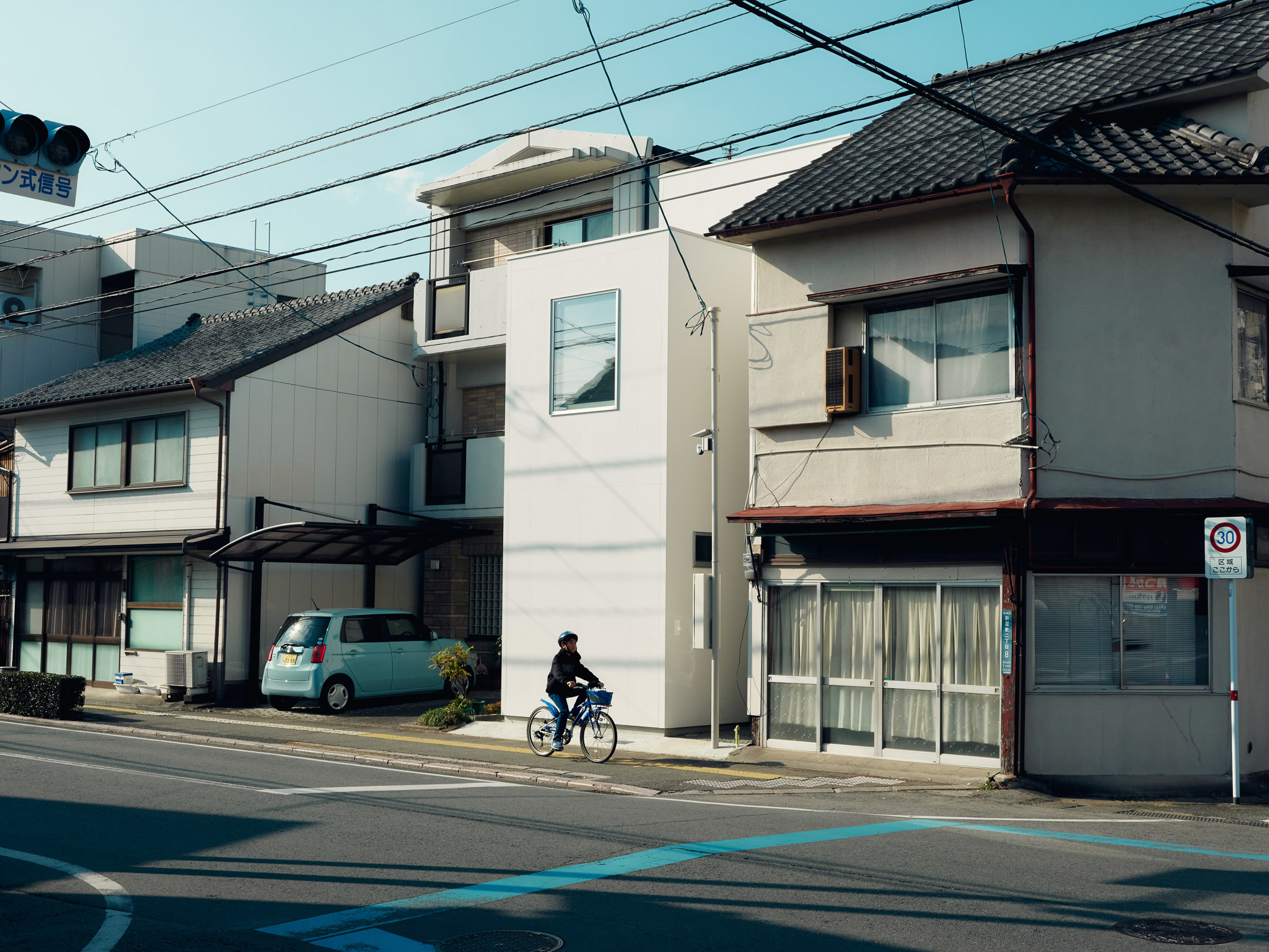 Exterior view of O-Studio showing three simple timber-clad volumes in a small residential neighbourhood.