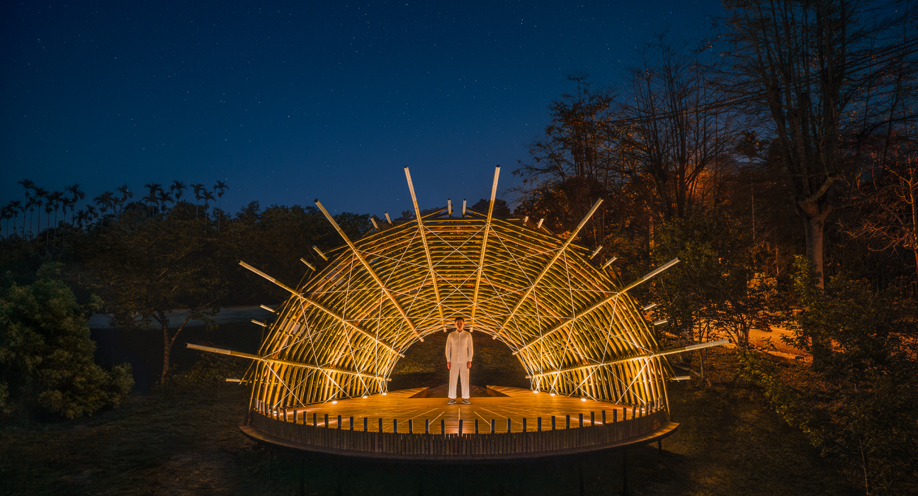 Bamboo Theater in Nantou illuminated with soft lighting, highlighting the interwoven structure of poles.
