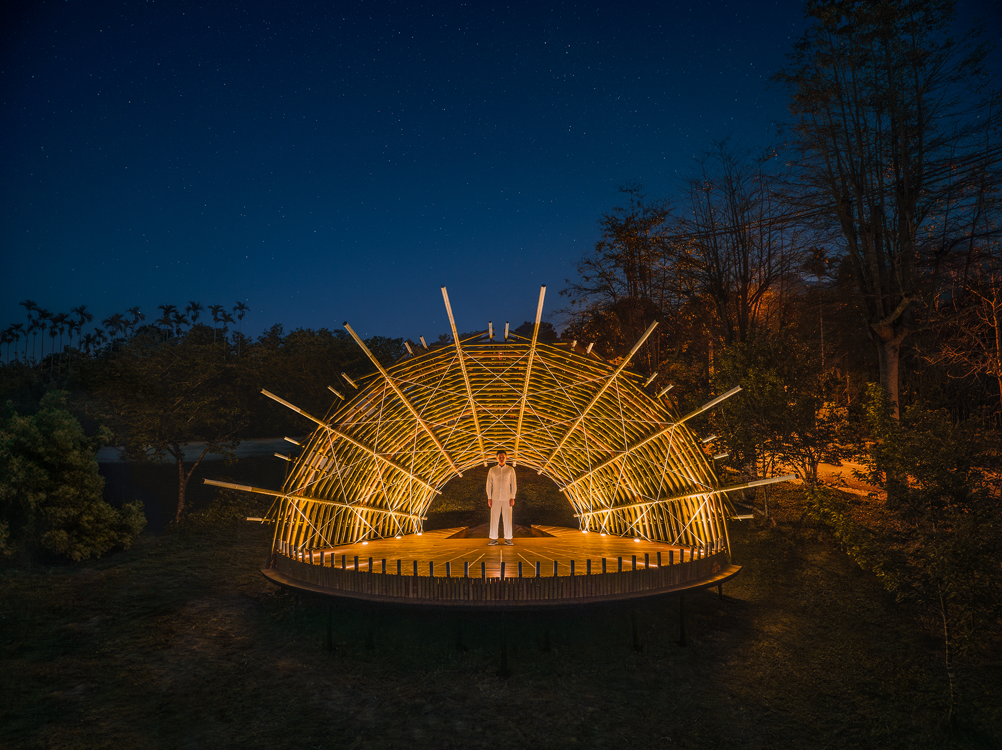 Bamboo Theater in Nantou illuminated with soft lighting, highlighting the interwoven structure of poles.